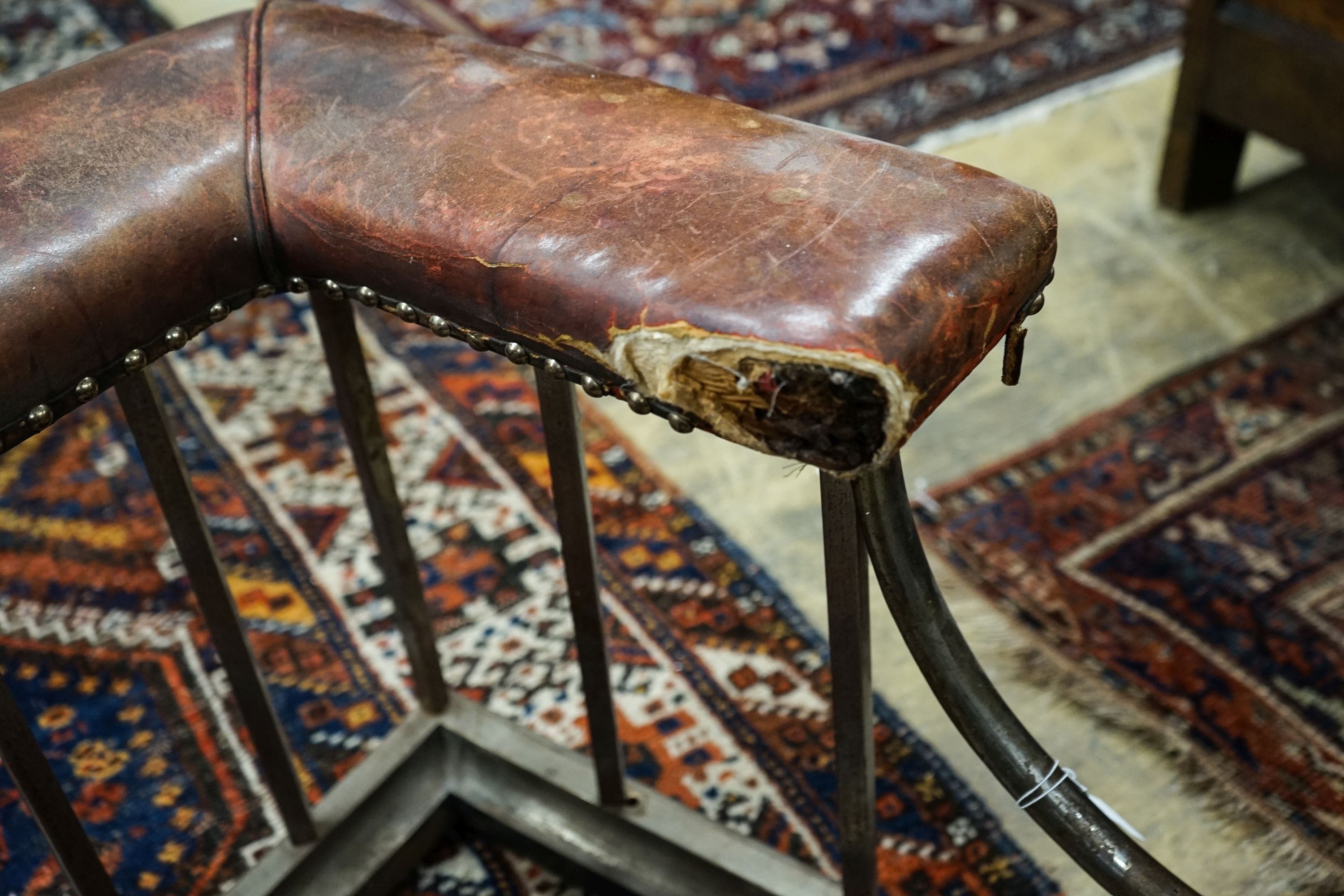 An early 20th century steel and burgundy leather club fender, length 140cm, depth 58cm, height 50cm